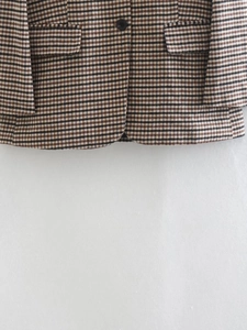 Detailansicht eines Blazers mit Hahnentrittmuster, schwarzen Knöpfen und Pattentaschen
