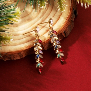 Golden leaf tassel earrings with colorful rhinestones on a festive pine wood background