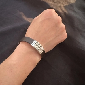 Gros plan d'un bracelet en cuir noir pour homme avec breloques gravées personnalisées en argent