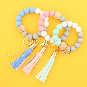 Detail of colorful silicone bead keychains with wood accents and tassels on yellow background