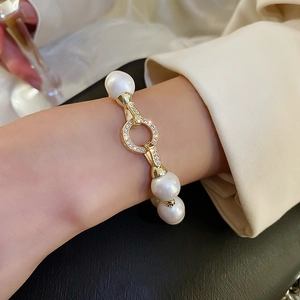 Elegant gold plated pearl bracelet with zircon clasp on woman's wrist in minimalist style