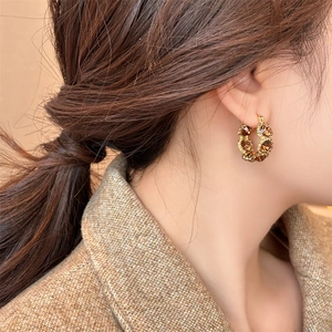 Detailed view of vintage gold-plated hoop earrings with amber crystals worn by a model