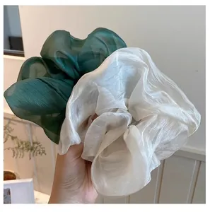 Detail of oversized dark green and ivory mesh scrunchies with pearlescent silk texture
