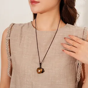 Long braided rope necklace with heart-shaped tiger eye stone pendant on female model