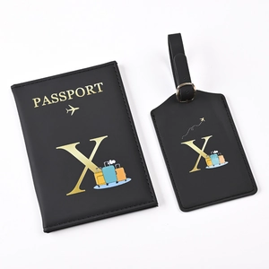 Close-up of black PU leather passport holder and luggage tag set with golden letter X