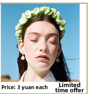 Outdoor model shot of a light green pleated satin headband under a clear blue sky