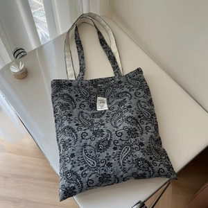 Detail shot of grey cotton linen tote bag featuring black Paisley floral embroidery prints