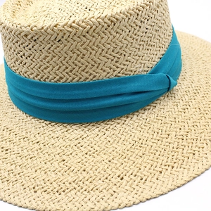 Close-up of tight-knit straw sun hat texture with a teal blue decorative ribbon