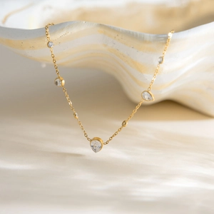 Détail du collier plaqué or 18K avec zircons blancs sur un support en coquillage