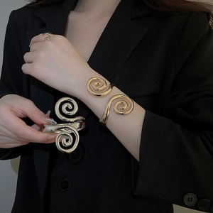 Detail view of bold metallic spiral bracelet and ring set in polished gold and silver finish