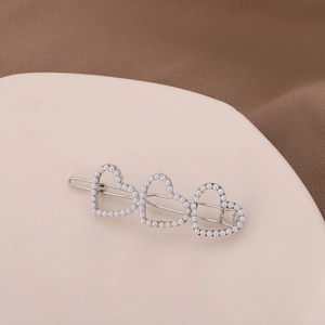 Détail de la pince à cheveux cœur en alliage avec perles blanches et finition argent