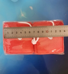 Detail of red plush car hanging dice showing 13-14cm measurement with a metal ruler