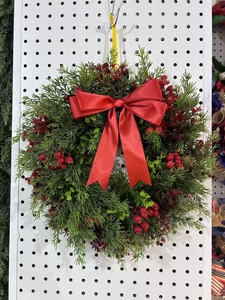 Close-up of a Christmas wreath with green cypress branches, red berries and a large red bow