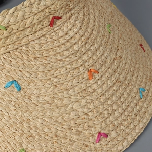 Detailaufnahme des Raffia-Strohgeflechts mit bunten V-förmigen Stickmustern auf Hut