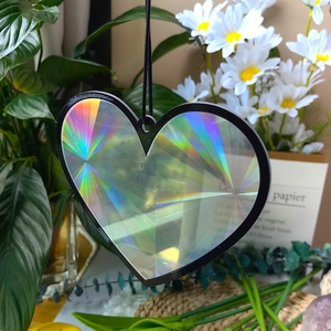 Close-up of heart-shaped holographic prism suncatcher with black frame in sunlight