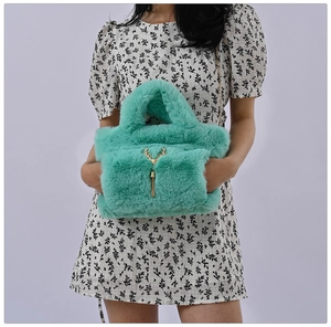 Detail view of mint green faux fur tote featuring golden antler decor and hand-warmer pocket