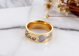 Detail of wide gold plated ring with Love engraving and zircon heart and arrow design