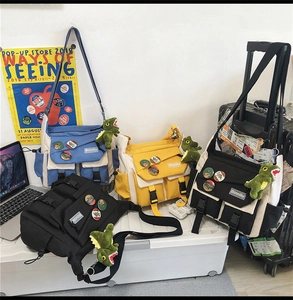 Detailed view of workwear messenger bags in blue, yellow and black with dinosaur charms