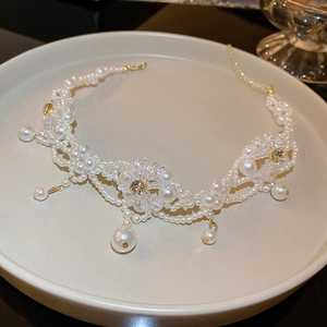 Close-up of pearl flower necklace with crystals on a white ceramic plate