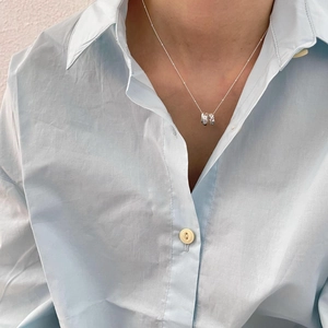 Detail of 925 silver necklace with interlocking triple ring pendant worn on neck
