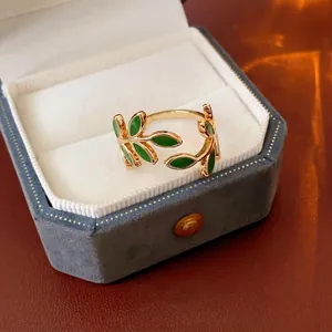 Adjustable leaf open ring in gold finish with green enamel details on velvet box