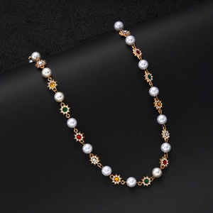 Macro detail of gold flower necklace with colorful crystals and white pearls on black background
