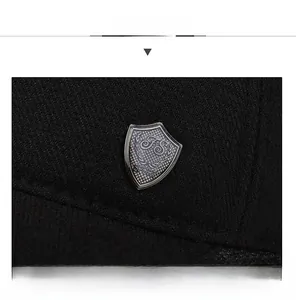 Detail of black baseball cap showing sandwich shaped peak and metal shield emblem