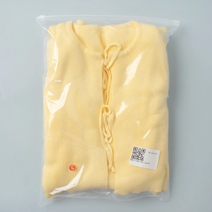Close-up of yellow knit cardigan with tie-up closure in S size retail packaging