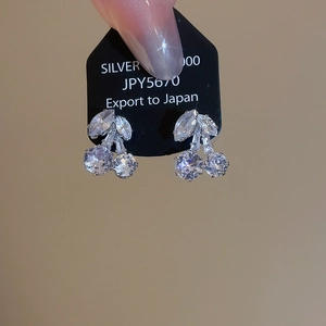 Macro shot of silver cherry earrings featuring zircon stones and 925 silver tag