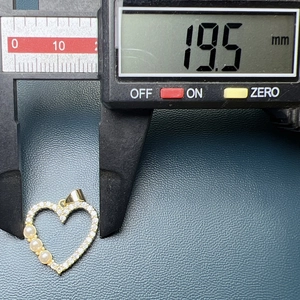 Detailed view of a heart pendant with pearls and zircons measured at 19.5mm by a caliper