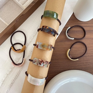 Acetate geometric hair rings set with tortoise shell and pearl patterns on wood base