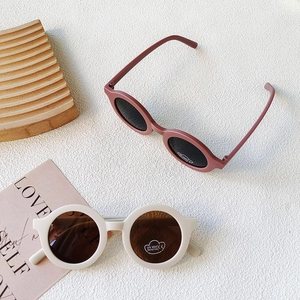 Close-up of retro round frame sunglasses with UV400 protection stickers on white surface