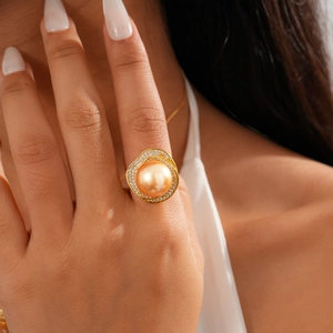Close-up of a large gold pearl ring with shimmering zircon petals on a model's finger
