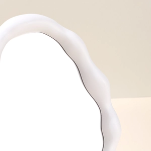 Close-up of a white cloud-shaped vanity mirror featuring a wide wavy plastic frame