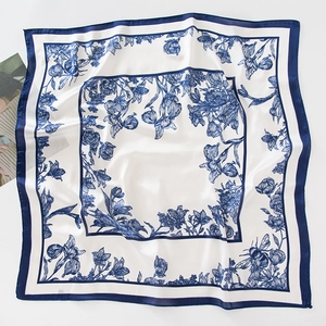 Flat lay of square silk scarf with blue floral and insect print on white background