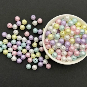 Detailed top view of assorted colorful textured ABS faux pearl beads in a small white bowl
