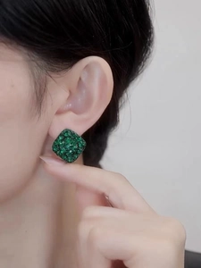 Close-up of elegant square emerald green earrings with pavé setting worn by model