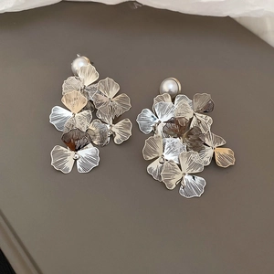 Detail of metal ginkgo leaf earrings with layered brushed texture and pearl stud