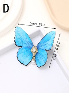Macro view of a blue butterfly brooch with gold detailing, pearl drop and dimensions