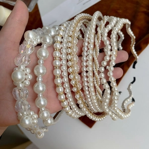 Close-up of various elegant faux pearl and crystal headbands in white and gold