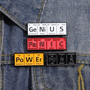 Detail of Genius and Panic chemistry enamel pins set on dark blue denim fabric