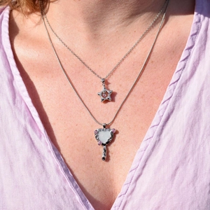 Silver layered necklaces with star and hand mirror pendants on a female model