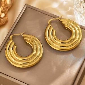 Macro shot of three-layered ribbed gold chunky hoop earrings on a velvet display