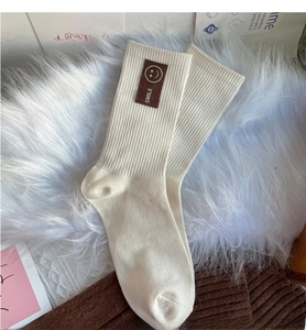 Gros plan de chaussettes en maille côtelée crème avec étiquette smile en cuir brun