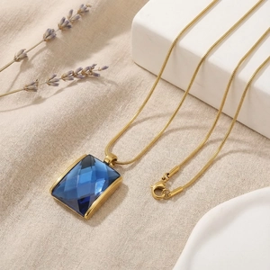 Detailed macro view of faceted dark blue square pendant on a 18K gold plated snake chain