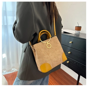 Detail view of khaki monogram bucket bag with tan leather patches and gold hardware