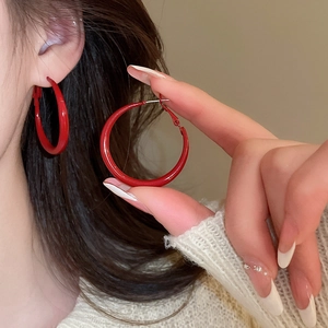 Detail of red lacquer hoop earring showing the glossy mirror finish and ear hook design