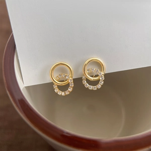 Detail of gold nested hoop earrings with cubic zirconia on white card display