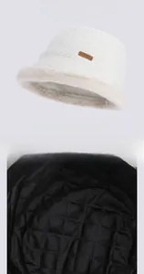 Detail of white plush bucket hat with warm black quilted lining and leather logo tag
