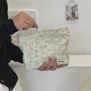 Floral canvas makeup bag in mint green with orange flowers and a woven brand label